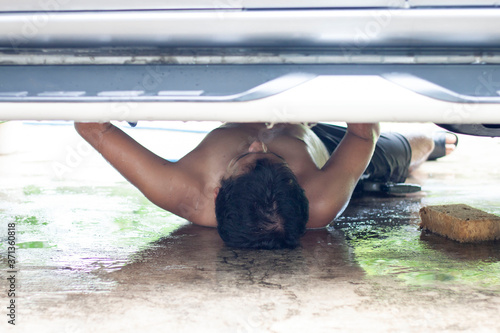 Bilde på lerret A man lying down and washing the undercarriage car.