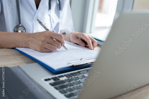 Doctor writing a prescription or health certificate and medical document in hospital 