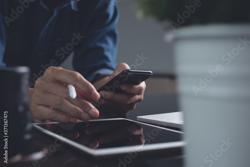 Casual business man using mobile phone while online working on computer devices