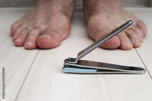 Nail clipper on the floor and a male foot.