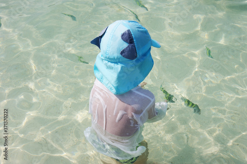 Little boy is catching bright stripped fish in transparent turqiouse water of Indian ocean. Traveling concept. acquaintance with the underwater world for children photo