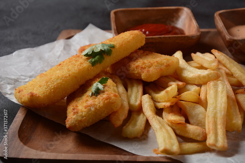 Traditional English Food - Fish and Chips. Fried fish filets and crispy French fries served with ketchup and homemade tarter sauce.