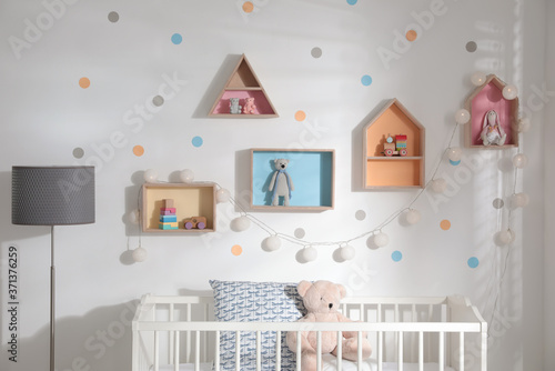 Cute children's room with house shaped shelves and crib. Interior design