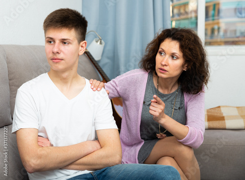 Worried mother scolding upset teenage son at home. Family conflicts concept..