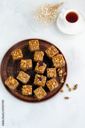 Chocolate fudge bars with nuts on a brown plate on a white background. Clean eating concept. Raw vegan dessert. Flat lay