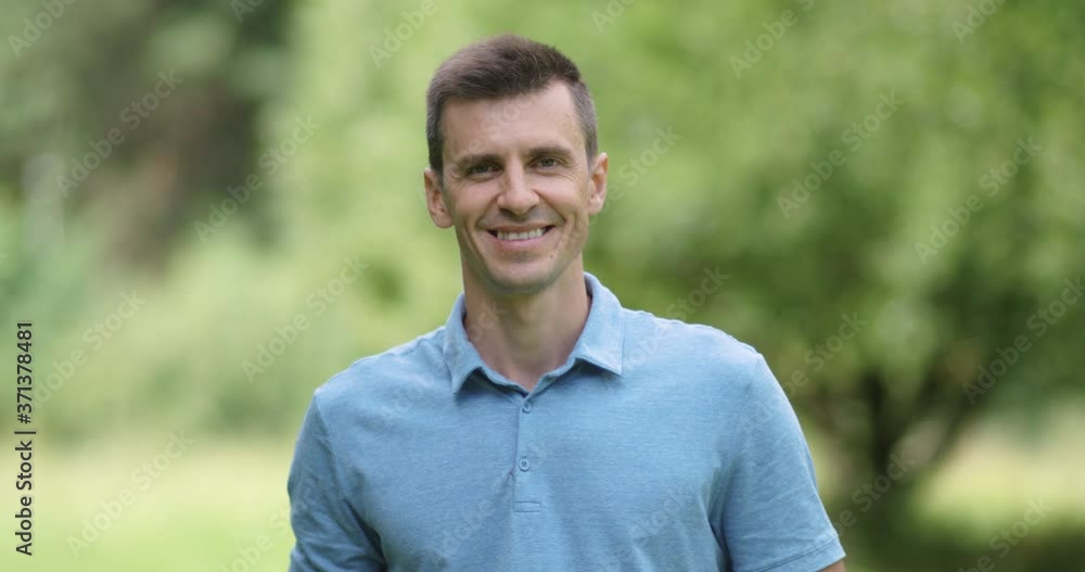 Portrait of an adult man on a blurred nature background, a view of a man's smiling face against a forest background, slow motion. Portrait of an adult man on a blurred nature background, a view of a man's smiling face against a forest background, slow motion.