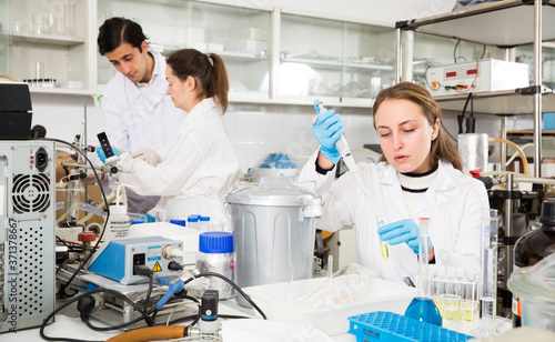 Professional female chemist working in laboratory, mixing reagents in test tube with lab pipette