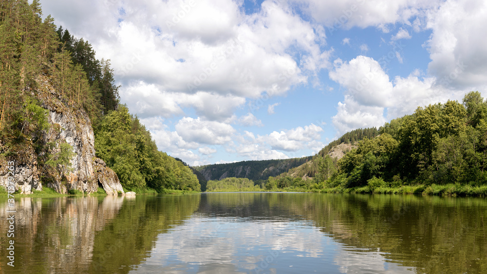 Panoramic view of water surface from the middle of Belaya mountain river. calm summer weather, clear cloudy sky. beautiful reflection of sky in water