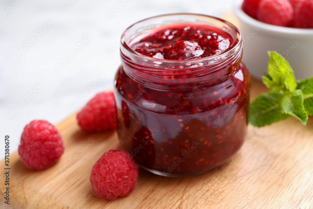 Delicious jam and fresh raspberries on wooden board, closeup Delicious jam and fresh raspberries on wooden board, closeup
