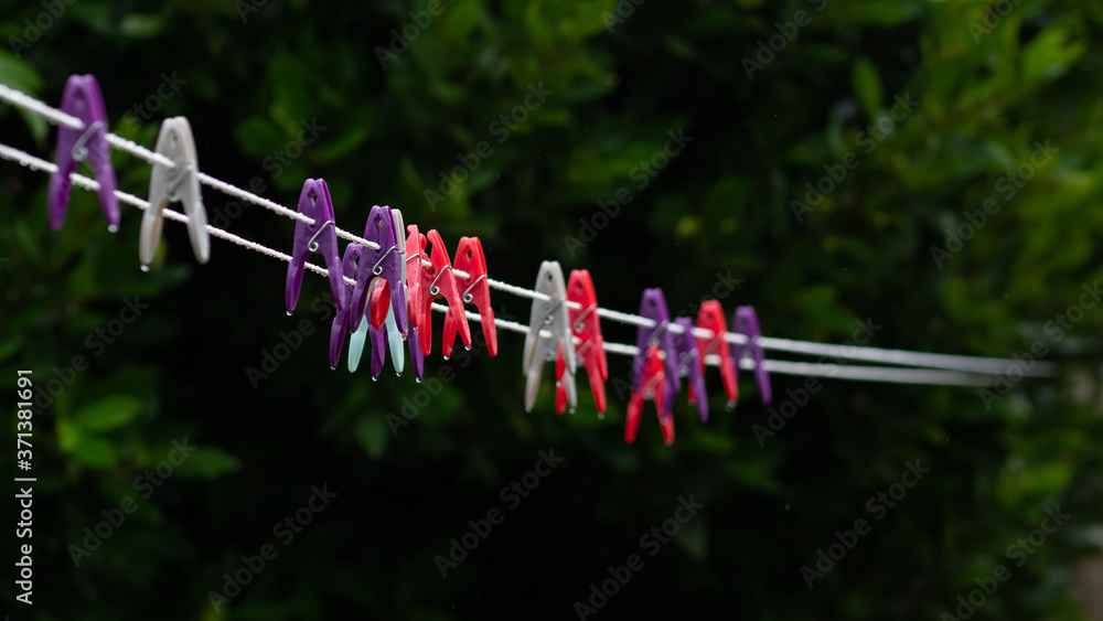 Colourful clothes pegs left out on a washing line in a sudden rain shower Colourful clothes pegs left out on a washing line in a sudden rain shower