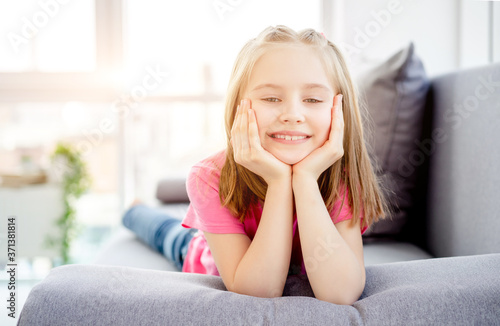 Smiling little girl lying on sofa in bright apartment