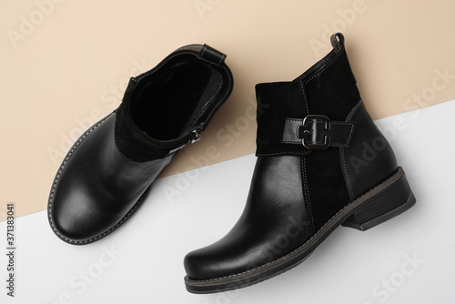 Stylish black female boots on color background, flat lay