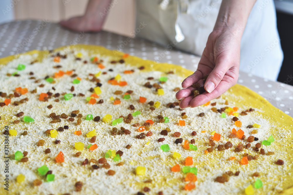woman's hand sprinkles the dough with candied fruits and raisins woman's hand sprinkles the dough with candied fruits and raisins