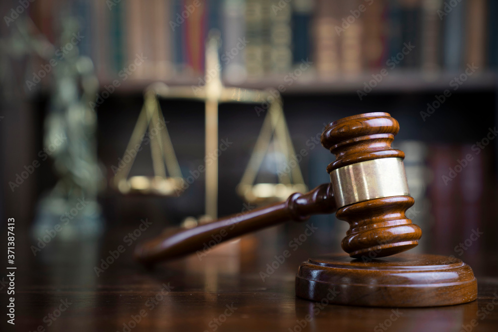 Law theme. Judge chamber. Gavel and scale on brown shining desk. Collection of legal books in the bookshelf. Law theme. Judge chamber. Gavel and scale on brown shining desk. Collection of legal books in the bookshelf.