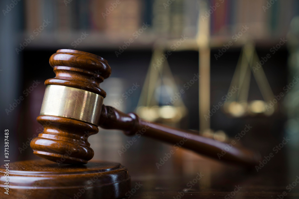Law theme. Judge chamber. Gavel and scale on brown shining desk. Collection of legal books in the bookshelf. Law theme. Judge chamber. Gavel and scale on brown shining desk. Collection of legal books in the bookshelf.