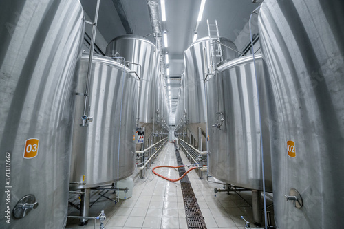 Row of tanks in brewery. Fermentation in brewery tanks with beer for brewing. Modern beer factory. Big steel tanks for storage.