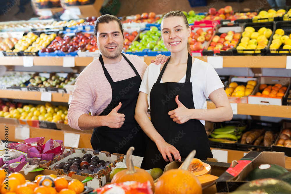 Adult man and woman with pumpkin wearing apron on the supermarket