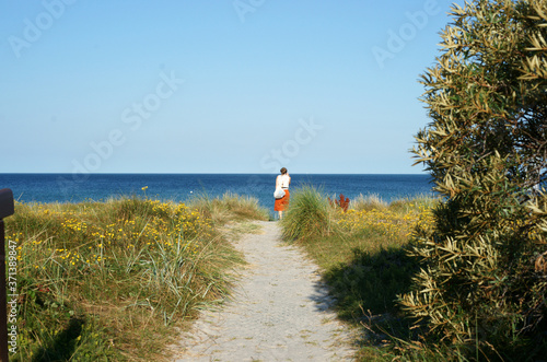 Woman takes a beach walk along the dunes of holiday island Hiddensee in Germany 