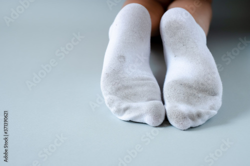 Pair of child feet in dirty stained white socks. dirty socks Pair of child feet in dirty stained white socks. Kid soiled socks while playing outdoors. Children clothes bleaching and.