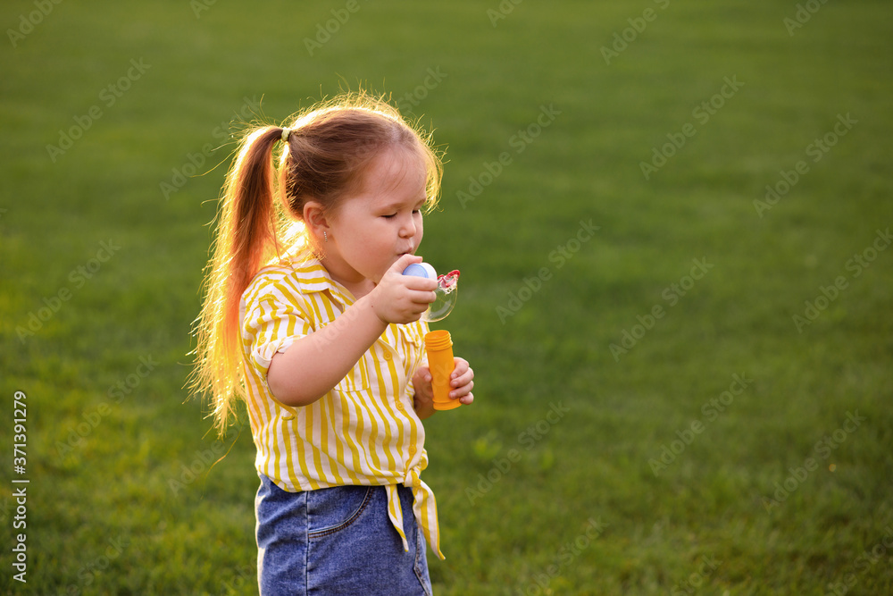 Happy little girl 4-5 years old plays with soap bubbles in the summer in the park. Children's lifestyle. Happy little girl 4-5 years old plays with soap bubbles in the summer in the park. Children's lifestyle.