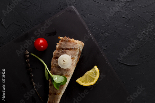 Fish fried on the grill and served on a plate with fresh vegetables photo