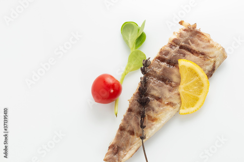 Fish fried on the grill and served on a plate with fresh vegetables photo