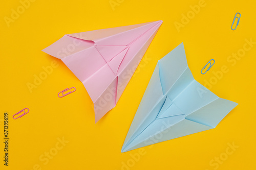 Minimalism  two blue and pink paper airplanes with paved path on yellow background  flat lay with copy space