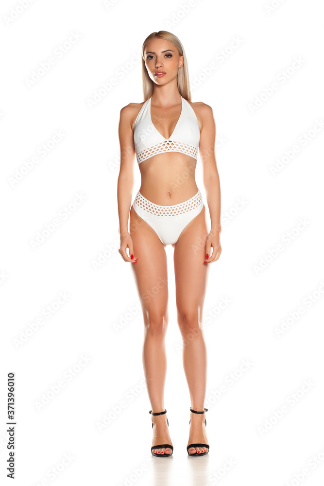 Woman in white bikini posing in studio on white background. Woman in white bikini posing in studio on white background.