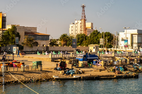 Port Sudan, Sudan. Busy coast in a harbor in Port Sudan, with sudanese people trading goods, exchanging, fishing, spending time and working. Old buildings of the city in the background. photo