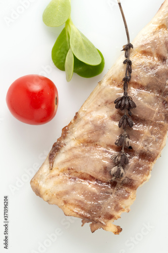 Fish fried on the grill and served on a plate with fresh vegetables photo