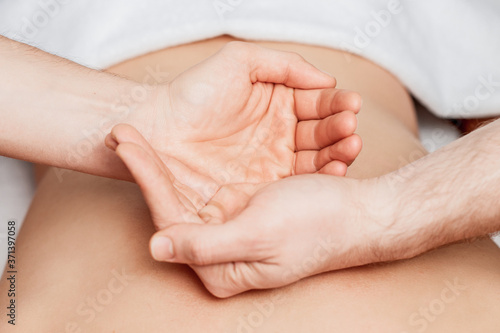 Palms of hands on human back by massager during hands show yin and yang.