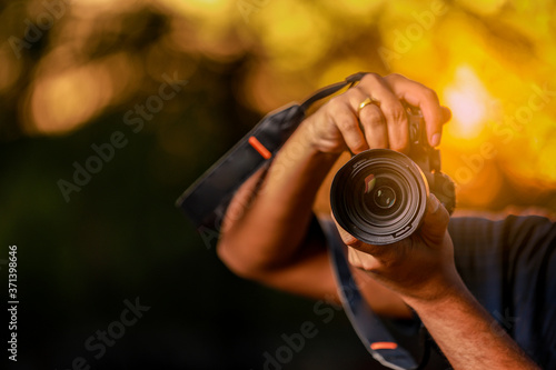 Closeup of a black camera holding by Photographer's hand with sunset background photo