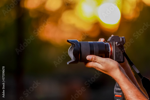Closeup of a black camera holding by Photographer's hand with sunset background photo