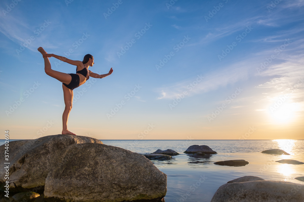 Anonymous woman balancing on stone in Warrior pose