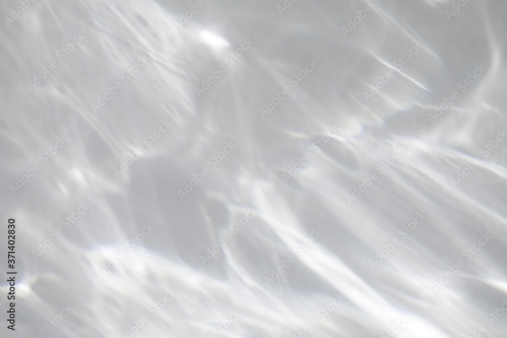 Obraz premium Blurred water texture overlay effect for photo and mockups. Organic drop diagonal shadow and light caustic effect on a white wall. Shadows for natural light effects