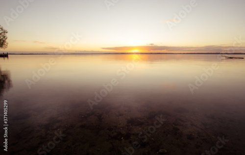 Sonnenaufgang am See bei ruhigen Gew  sser mit Treibholz