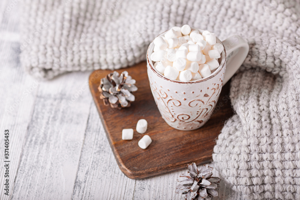 Mug with coffee and marshmallow, knitted scarf on wooden table. Autumn mood. Cozy autumn composition. Hygge concept Mug with coffee and marshmallow, knitted scarf on wooden table. Autumn mood. Cozy autumn composition. Hygge concept