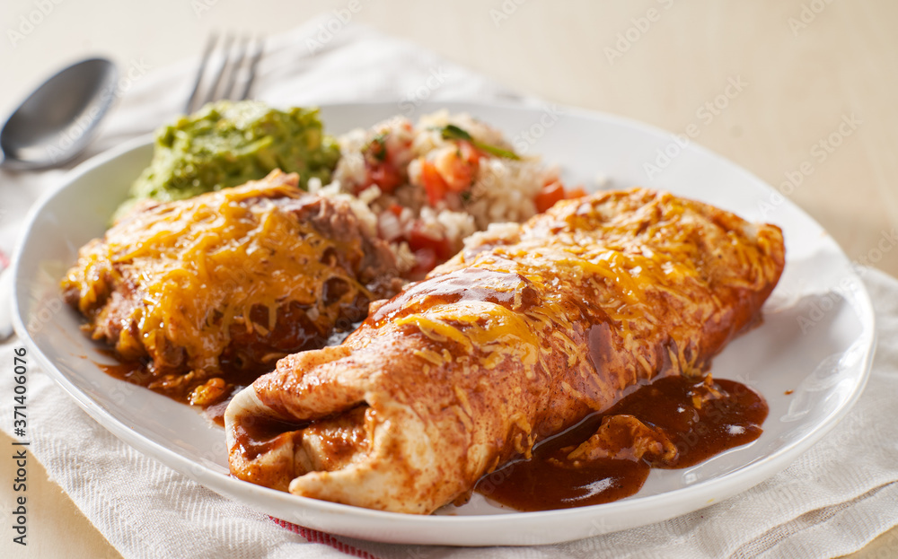 mexican wet burrtio platter with red enchilada sauce, refried beans, rice and gaucamole mexican wet burrtio platter with red enchilada sauce, refried beans, rice and gaucamole