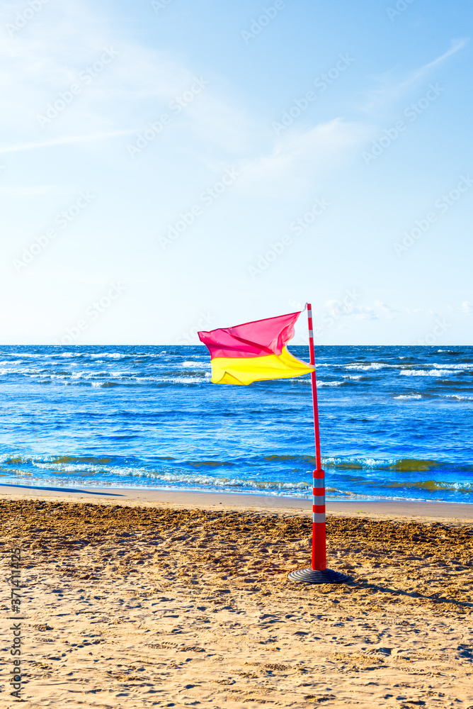 Red, yellow life saving flag on the sea beach on blue sky Red, yellow life saving flag on the sea beach on blue sky
