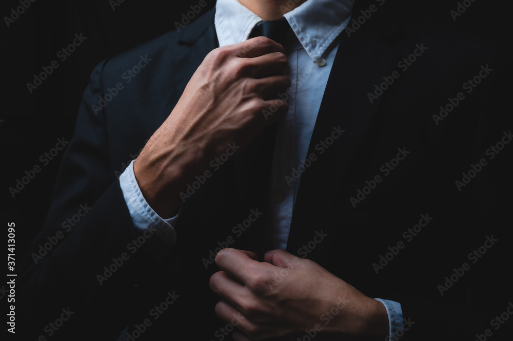business man in black suit and adjusting his necktie