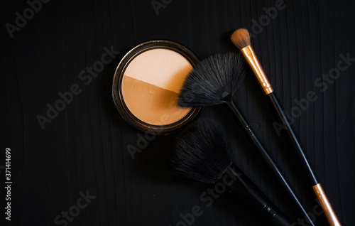 orange sponge and makeup shadow brushes on a dark background