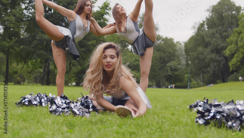 Fotografie Beautiful cheerleading girls stretching and warming up before practicing outdoor