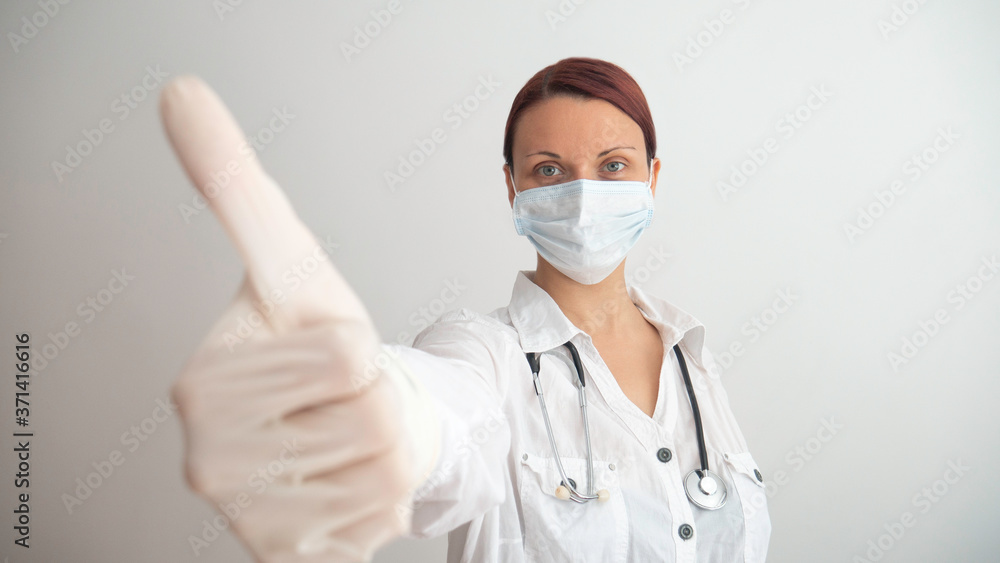 The female doctor gives a thumbs up with her hand in a rubber glove. The female doctor gives a thumbs up with her hand in a rubber glove.