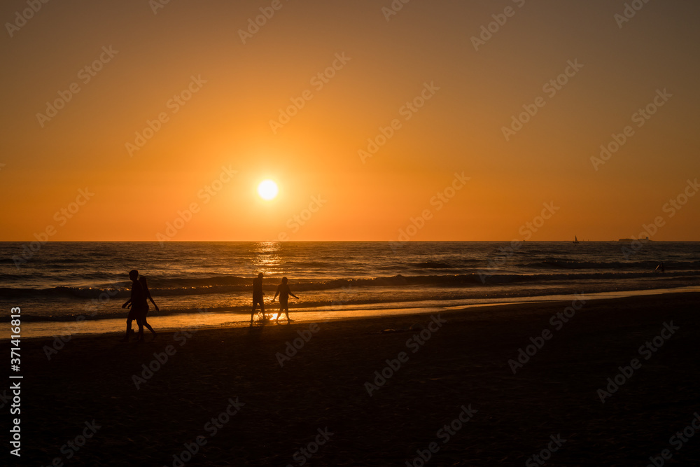 Silhouettes of people taking photos at sunset on the beaches of Cadiz, Spain