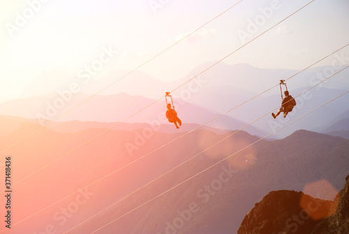 man on zip line. extreme sport in mountains at the sunset