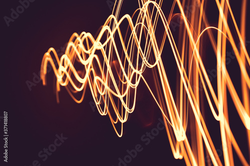 Painting with light at night, bright orange line shape on a black backgroud. The light source moves within the frame.
