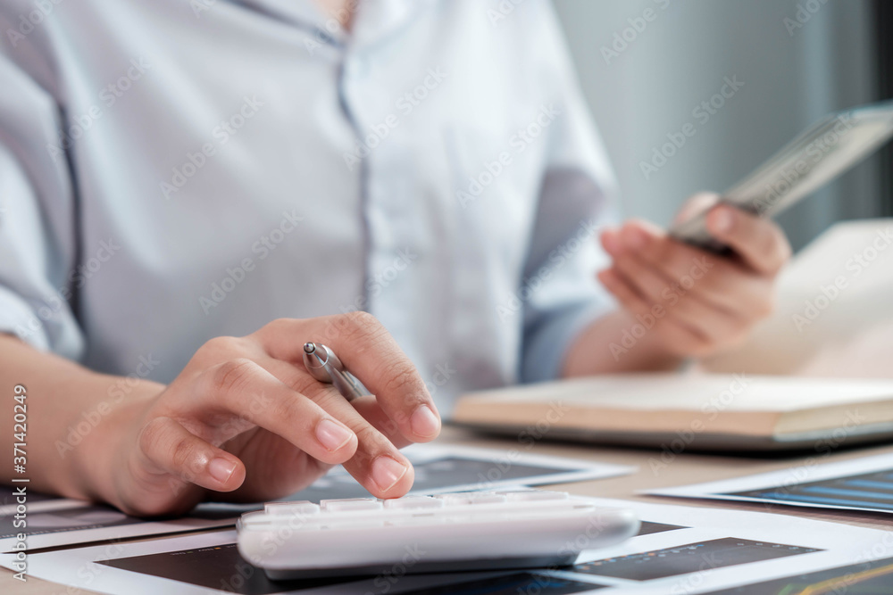 Fototapeta premium businesswoman or an accountant uses a calculator to calculate prices. And customer proposals for future financial spending for balance and prosperity, using graphs to analyze