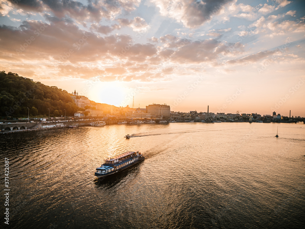 Fototapeta premium Sunset cityscape in Kyiv, Ukraine. Poshtova square in Kiev. Landscape view of the Dniper river against golden hour skies