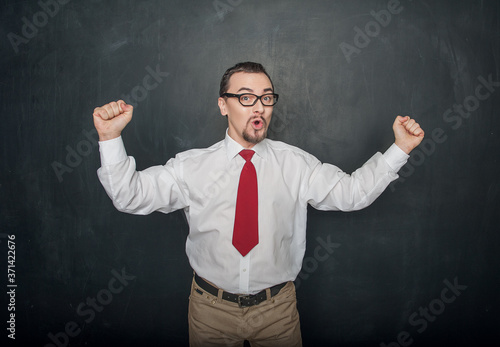 Successful handsome happy man with raising arms on chalkboard