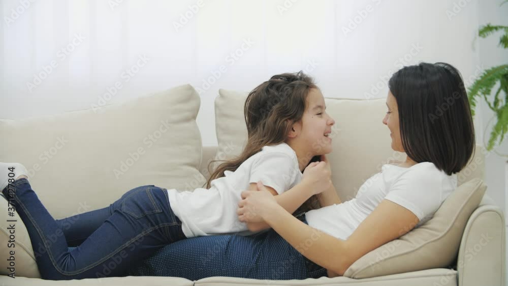 Conversation of cute daughter and her mother, lying on the sofa, petting each other on head. Conversation of cute daughter and her mother, lying on the sofa, petting each other on head.